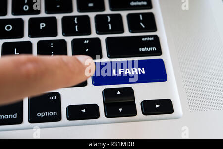 Computer notebook con tastiera imparare tasto blu, argento portatile con tastiere nero, dito desidera premere il tasto Foto Stock