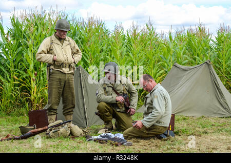 Ricostruzione dell'esercito degli Stati Uniti della seconda guerra mondiale. Rievocatori in uniforme da battaglia d'epoca con tenda e attrezzatura Foto Stock