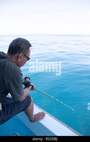 L'uomo la pesca in barca su flottante blu acqua di mare Foto Stock