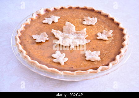 Vista laterale del pane appena sfornato tradizionale torta di zucca dolce per la festa del Ringraziamento su sfondo bianco. Decorativo foglie di pasta sulla parte superiore. Foto Stock