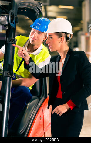 Driver di carrello elevatore a forche e il collega in stock di freight forwarding Foto Stock