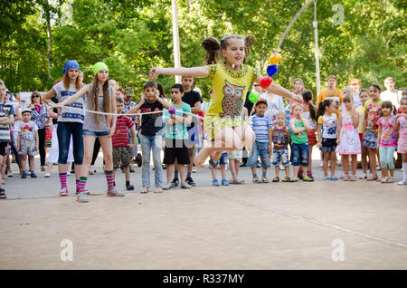 Komsomolsk-su-Amur, Russia - 1 agosto 2016. Pubblico aperto Railroader's day. ragazzina salta su una fune detenute da ragazze in costumi del pirata al partito del pirata Foto Stock