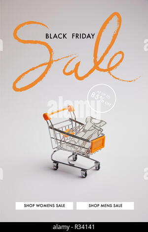 Vista ravvicinata del carrello con poco le merci fatte di carta su uno sfondo grigio, venerdì nero vendita iscrizione Foto Stock