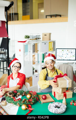 I progettisti di felice in Santa caps la preparazione di regali per Natale e rendendo le decorazioni Foto Stock