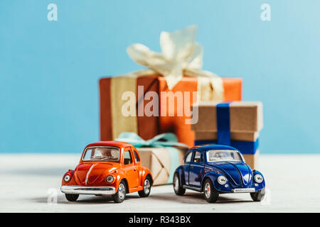 Close-up shot di automobili giocattolo con natale confezioni regalo su sfondo blu Foto Stock