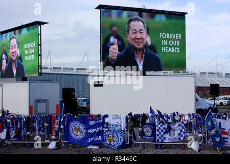 Il calcio sciarpe drappeggiati oltre le barriere di fronte ad un immagine di Vichai Srivaddhanaprabha presso il suo memoriale vicino al King Power Stadium di Leicester Foto Stock