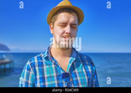 Ragazzo con protezione solare Crema lozione sulla faccia. L'uomo utilizzando abbronzatura solare Crema per il corpo sulla spiaggia d'estate. Foto Stock