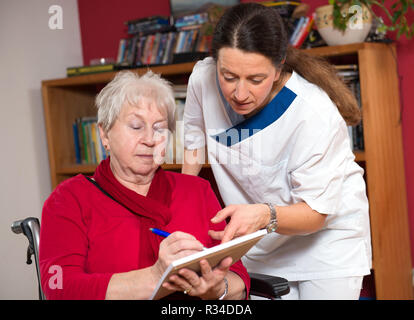 L'infermiera aiutando senior citizen in un modulo Foto Stock