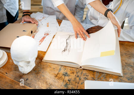 Phisicians studio medico con libro e disegni sul tavolo per interni. Vista ravvicinata incentrata sul libro Foto Stock