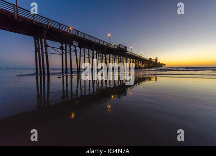 La riflessione di un molo sulla superficie dell'oceano mentre il sole tramonta in Oceanside, California, Stati Uniti d'America Foto Stock