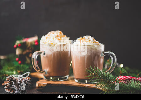 Cioccolata calda con panna montata su sfondo nero circondato con abete rami. Hot drink di Natale. Comfort food per vacanze invernali. Copia sp Foto Stock