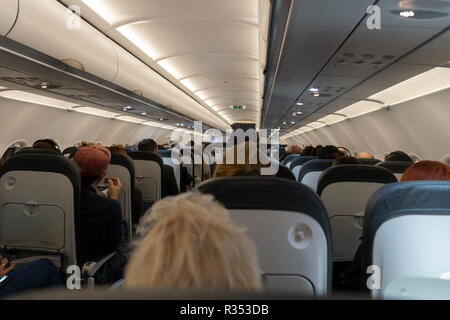 I passeggeri seduti nella cabina di un aereo di linea di passeggeri su un British Airways volo serale Foto Stock