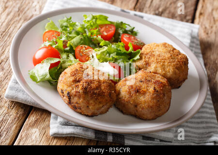 Saporite carni suine danesi carni macinate le polpette in panatura con verdura fresca insalata di close-up su una piastra sul tavolo orizzontale. Foto Stock