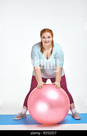 Divertente immagine di divertenti, dai capelli rossi, chubby la donna che è in possesso di una sfera Foto Stock