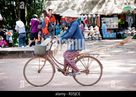 Angkor Wat, Cambogia - 30 ottobre 2011:cambogiani donna in bicicletta attraverso un villaggio. Foto Stock