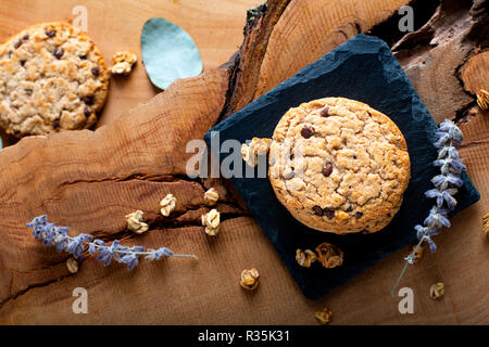 Concetto di cibo organico artigianale cioccolato cookie su pietra ardesia su piastra in legno rustico sfondo con spazio di copia Foto Stock