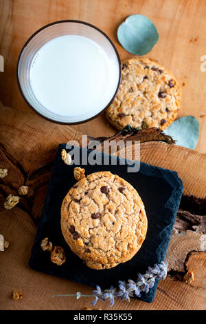 Concetto di cibo organico artigianale cioccolato cookie su pietra ardesia su piastra in legno rustico sfondo con spazio di copia Foto Stock