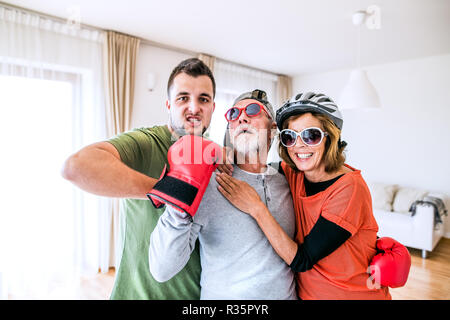 Una coppia senior con il nipote avente il divertimento a casa. Foto Stock