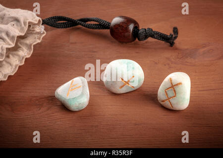 Rune dall'alfabeto Futhark, pietre con i simboli utilizzati in Wicca e altri magic e per la divinazione, lanciata da un sacchetto con un posto per il testo Foto Stock