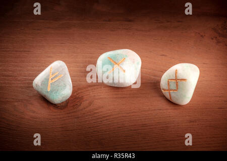 Norse rune, pietre con simboli utilizzati in Wicca e altri magic e per la divinazione, al buio su un sfondo rustico con un posto per il testo Foto Stock