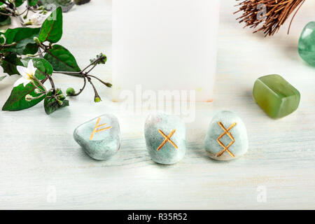 Norse rune, pietre con simboli utilizzati in Wicca e altri magic e per la divinazione, con una candela e cristalli con un posto per il testo Foto Stock