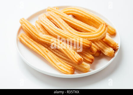Churros in un piatto bianco isolato su bianco Foto Stock