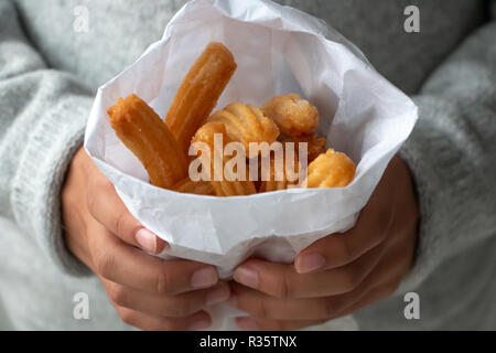 Bambina mani churros in un sacchetto di carta Foto Stock