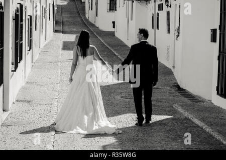 Sposa e lo sposo a piedi lungo la strada in un villaggio mediterraneo Foto Stock