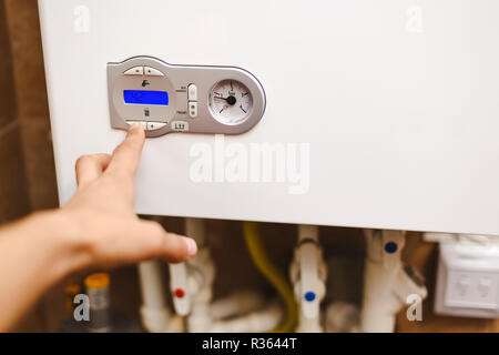 La persona che regola il calore nella zona centrale di caldaia di riscaldamento. La persona che regola la caldaia di riscaldamento. Foto Stock