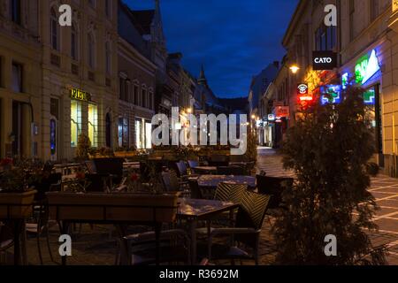 BRASOV, ROMANIA Novembre 1, 2017: vista della street cafe sulla piazza principale del centro storico della città di Brasov illuminate dai lampioni. Reggiseni Foto Stock