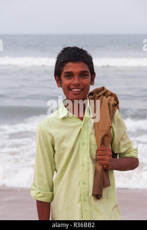 Chennai, India - 6 Settembre 2007: un sorridente ragazzo locale in posa per una foto al Marina Beach a Chennai con il mare agitato in background. Foto Stock