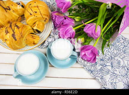 Delizioso e bella colazione - cornetti, caffè e un mazzo di tulipani di colore viola. Foto Stock