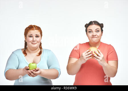 Chubby donne: una donna è in possesso di un sandwich,un'altra azienda un Apple Foto Stock