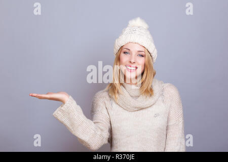 Giovane donna sorridente, presenta qualcosa in mano Foto Stock