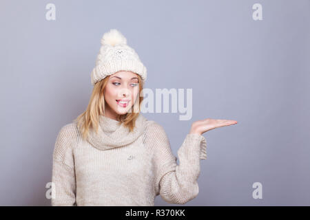 Giovane donna sorridente, presenta qualcosa in mano Foto Stock