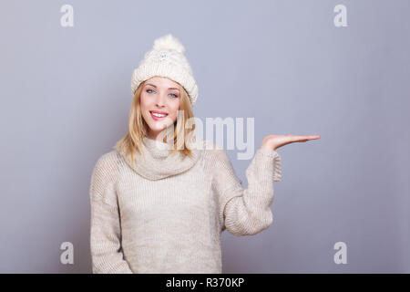 Giovane donna sorridente, presenta qualcosa in mano Foto Stock