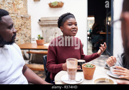 Giovane donna di parlare con gli amici in un bar alla moda cortile Foto Stock