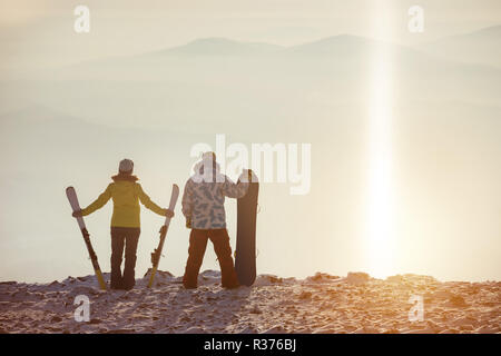 Sciatore e snowboarer sorge sulla cima della montagna a stazione sciistica Foto Stock