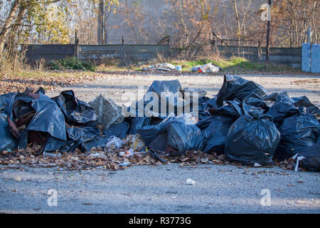 Ingresso di un parcheggio bloccato con sacchetti di plastica contenenti cestino, inquinare l'ambiente. Foto Stock