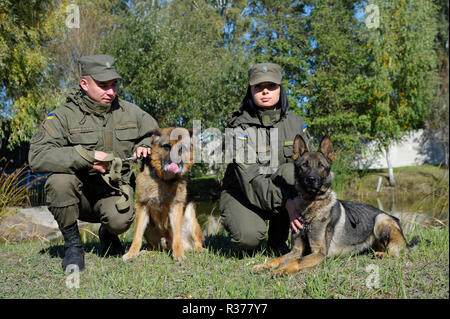 Presso il centro di Canino. I gestori di militari e cani di servizio seduti su un terreno dopo il training. Ottobre 18, 2018. Novo-Petrivtsi base militare, Ucraina Foto Stock