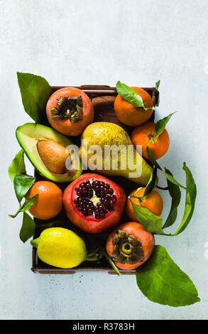 Diversi frutti di melograno, pera, mandarino, limone, avocado e persimmon con noce di cocco sul tavolo. base di nutrizione sana e succhi di frutta ogni giorno i Foto Stock