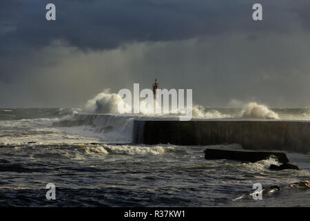 Mare tempestoso onde di oltre il molo e il faro con bella luce prima pioggia. Ave foce, a Vila do Conde, il nord del Portogallo. Foto Stock