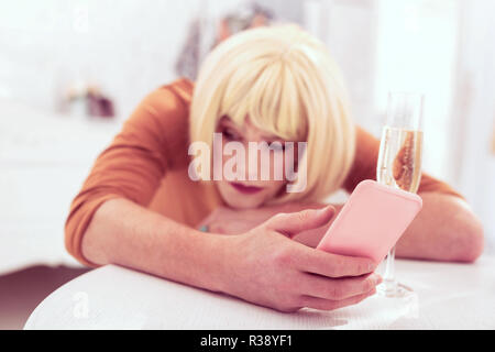 Interessante transgender con parrucca bionda rosa porta telefono cellulare Foto Stock
