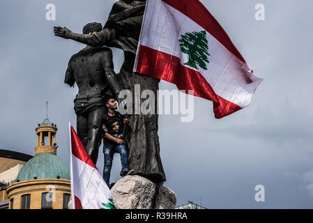 Beirut, Libano. 22 Novembre, 2018. Un manifestante visto in piedi accanto a statue tenendo un flag durante la protesta.Il clima è stato generalmente sgonfi come una manciata di manifestanti, quasi sopraffatti dai giornalisti sono stati riuniti presso il la Piazza dei Martiri a Beirut per protestare contro il cattivo stato del loro paese, dalla gestione dei rifiuti per l'economia, per cui essi dare la colpa al governo. Più detto che celebra l'indipendenza sotto tali circostanze si sente come uno scherzo di cattivo gusto. Essi ammettono che le cose cambieranno per il meglio, dicendo libanesi avrebbe protestato più ma sono stanco perché Foto Stock