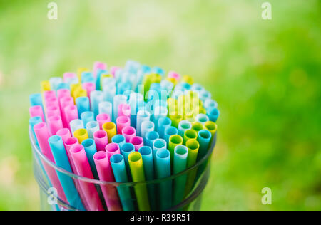 Luminosa colorata bevanda cocktail cannucce e tubi messi insieme nella grande vetro su erba verde estate sfondo. La preparazione alla festa Foto Stock