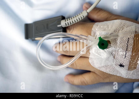 Chiusura del sensore SpO2 (capillare periferico della saturazione di ossigeno) e flebo IV sulla mano del paziente in corrispondenza della camera di ospedale. Foto Stock