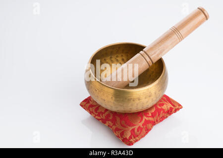 Il Tibetano Singing Bowl sul cuscino rosso isolato su sfondo bianco Foto Stock