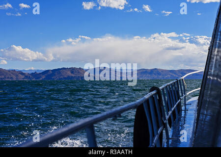 In barca a vela sul lago con le montagne a Puno, Perù Foto Stock