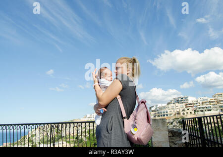 Giovane mamma single tenendo un mese baby boy, preoccupati di fronte l'espressione Mellieha, Malta Foto Stock