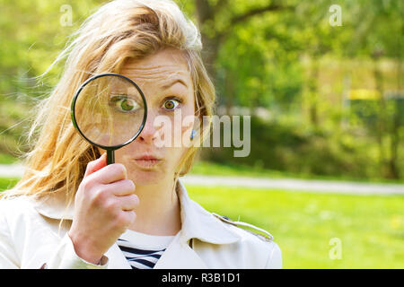 Giovane donna con lente di ingrandimento Foto Stock